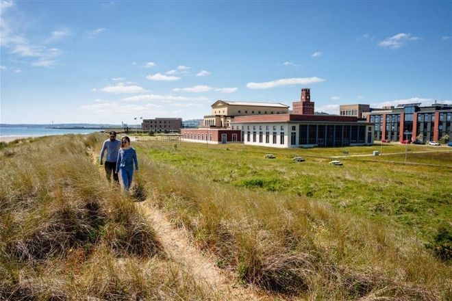 Two international students walking along the beach at Swansea University Campus.